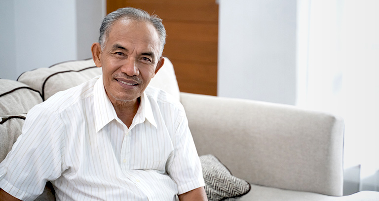 Smiling senior man seated on couch in his home