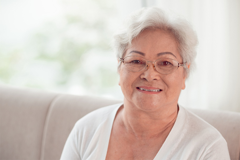 Senior woman seated on couch and smiling at camera