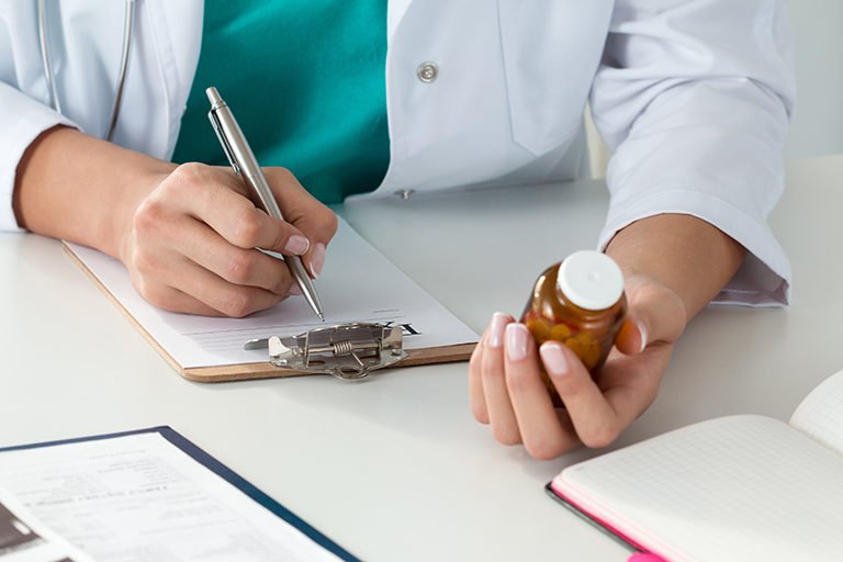 provider hands holding bottle and writing