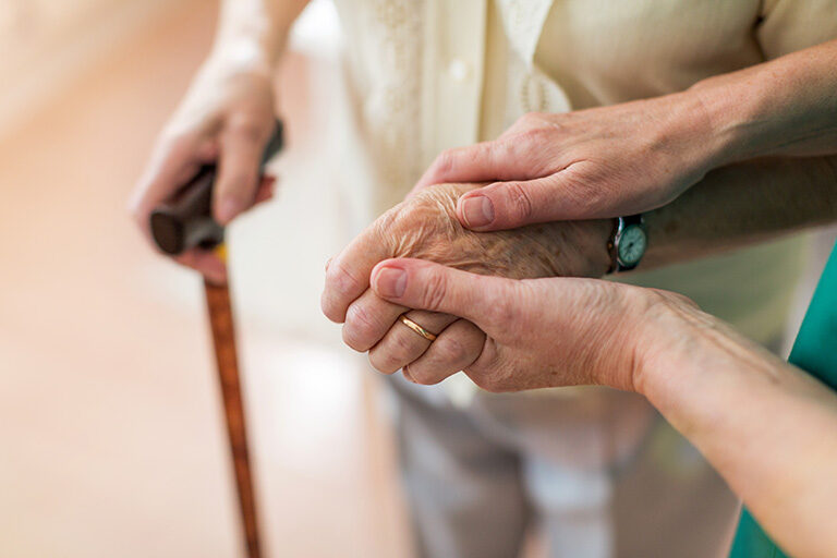 Image of caregiver holding the hand of an older adult