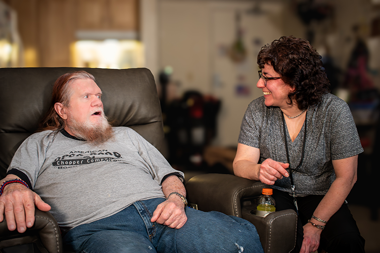 A photo of a CCA member sitting in his living room talking to his CCA care partner.
