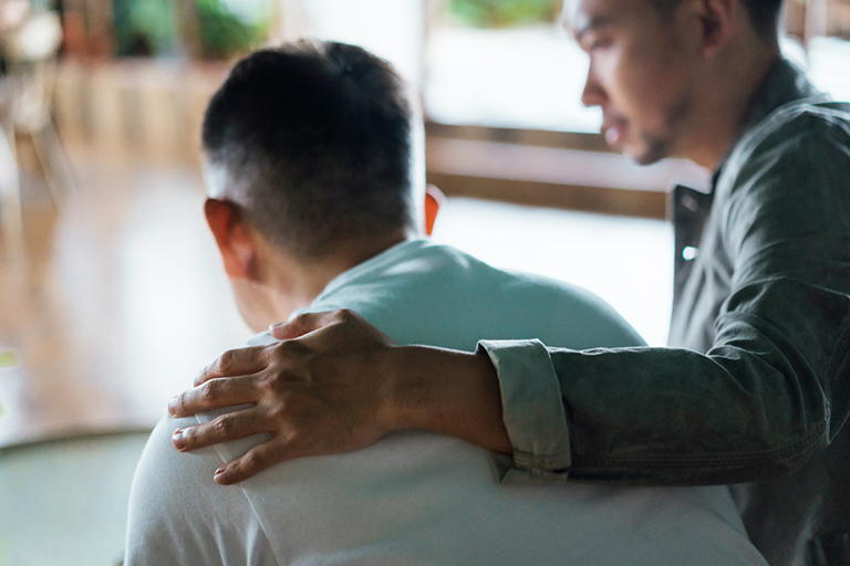 Chronic Stress and the Surprising Impact on Your Health A younger man with his hand over the shoulder of an older man who is in distress.