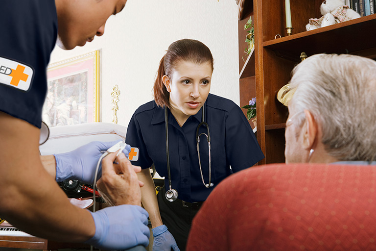 Female paramedic focused on senior patient in patient's living room
