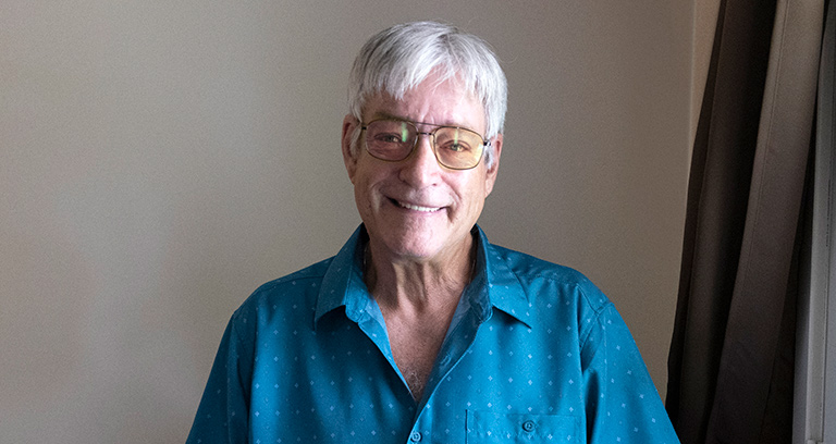 CCA member smiling while standing next to a window in his home