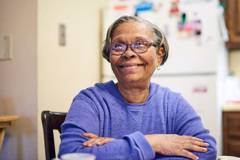 Senior CCA member smiling while seated at her kitchen table