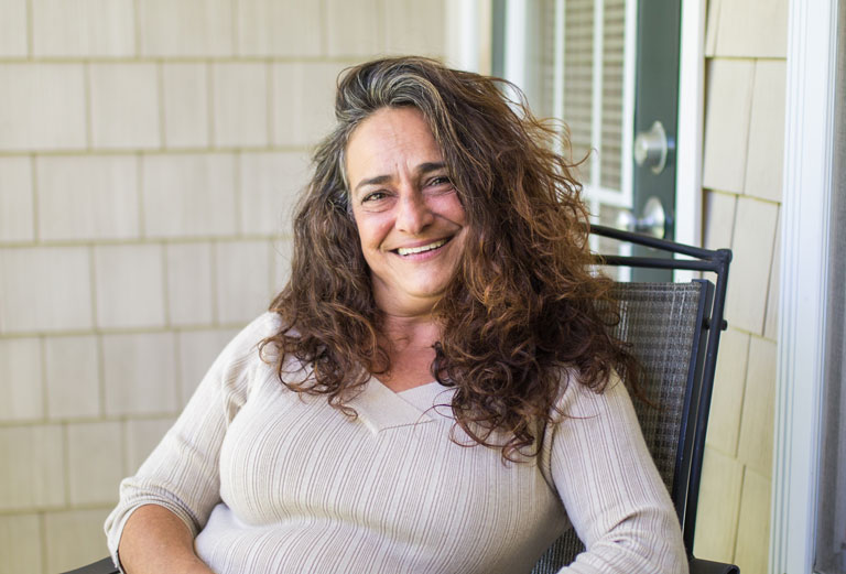 One Care female member smiling sitting on front porch