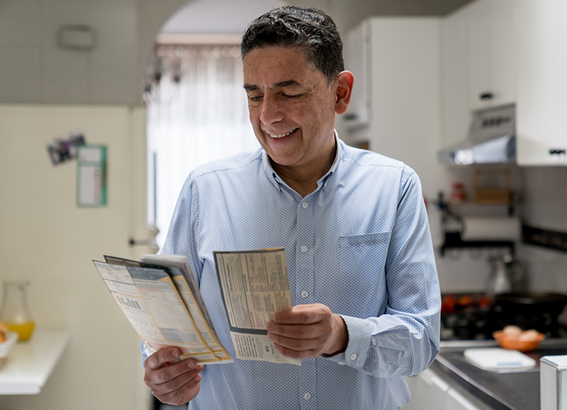 woman with shoulder length hair looking at mail on the doorstep with the door open.