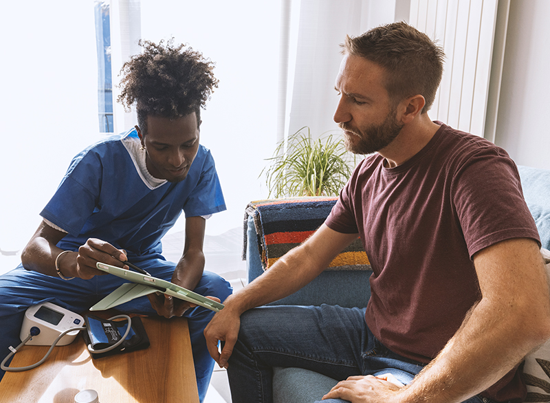two people in a home leaning over documents with medical equipment nearby