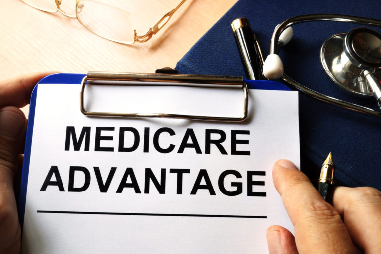 A clipboard with a piece of paper that says Medicare Advantage