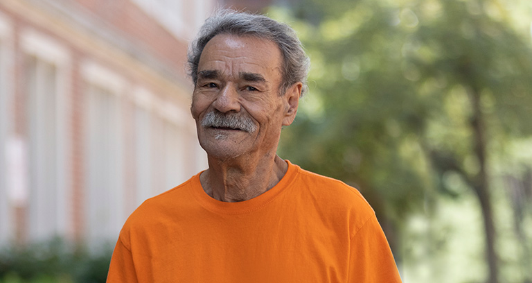 Senior man smiles as he walks outside his home