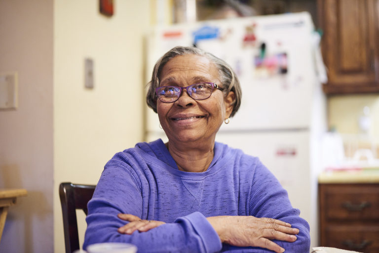 CCA member Shirley seated at her kitchen table, smiling