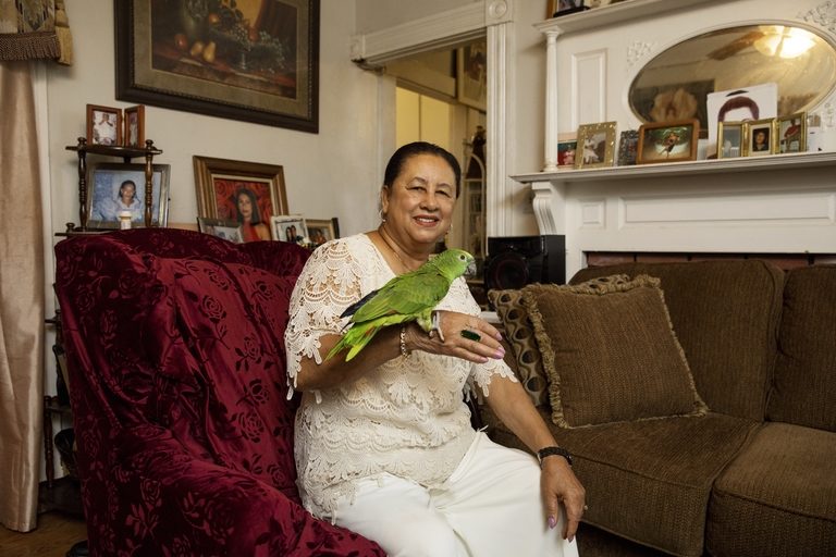CCA member AIDA in her living room with a bird perched on her hand