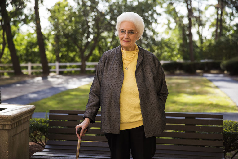 CCA SCO member Helene stands outside while leaning on a cane