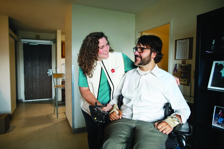 Young man in wheelchair at home talking to his CCA care partner