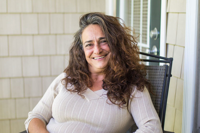 Lyne, a CCA member, sitting on her porch