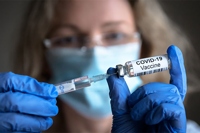 Female medical professional filling syringe from COVID-19 vaccine vial