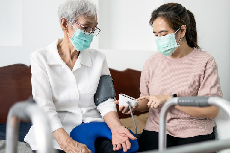 Senior woman has blood pressure taken by her caregiver