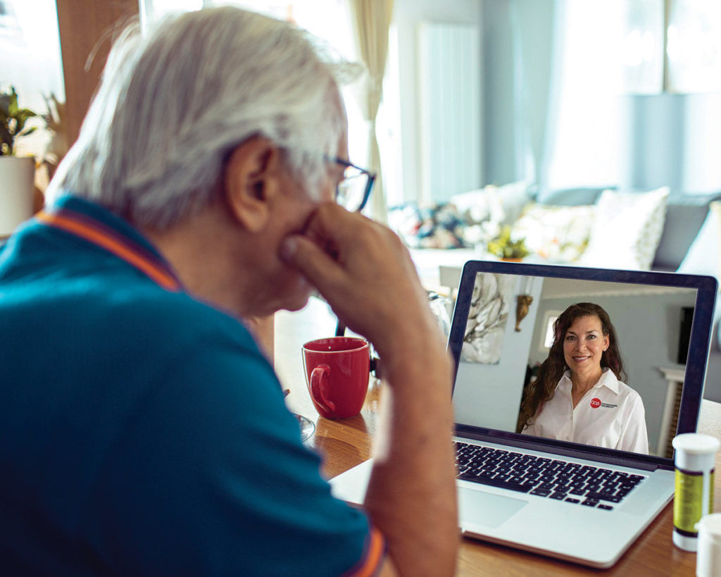 Elderly man participating in a virtual medical visit at home on his laptop