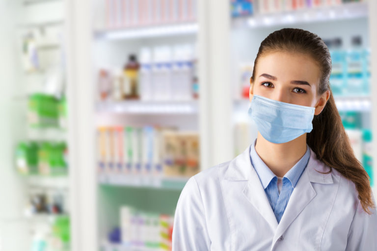 Young woman pharmacist wearing mask inside pharmacy