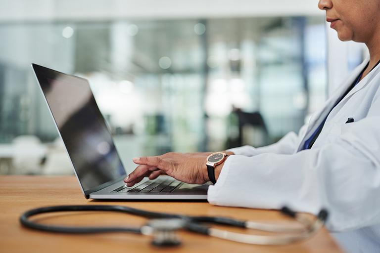 Closeup of African American doctor's hands typing on laptop keyboard