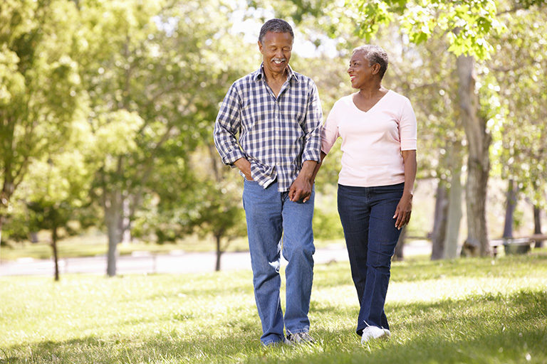 Senior man and woman holding hands while walking in a park