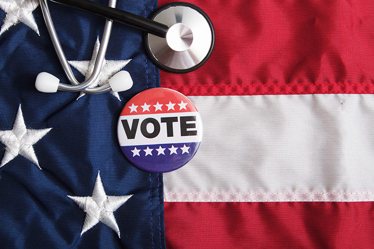 American flag with vote sticker and stethoscope lying on top