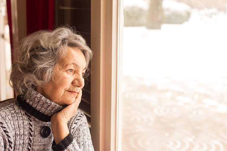 Image of a senior woman looking out her window