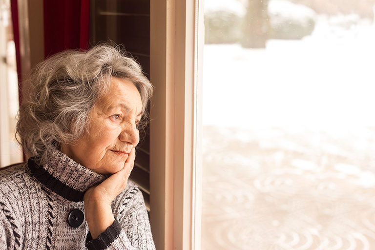 Image of a senior woman looking out her window