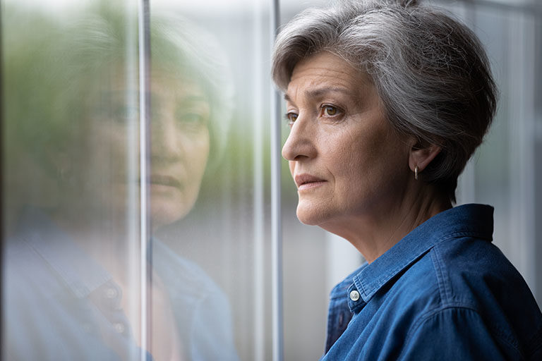 A woman looking outside of her window