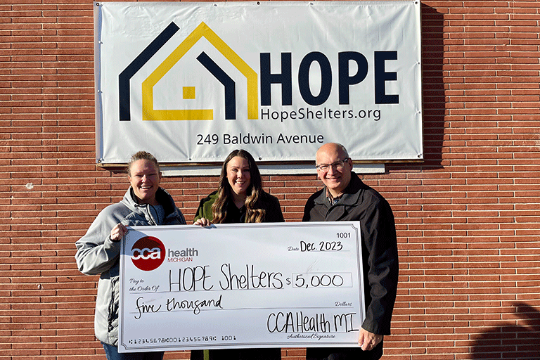 A photo of a CCA employee giving a large check to HOPE Shelters employees