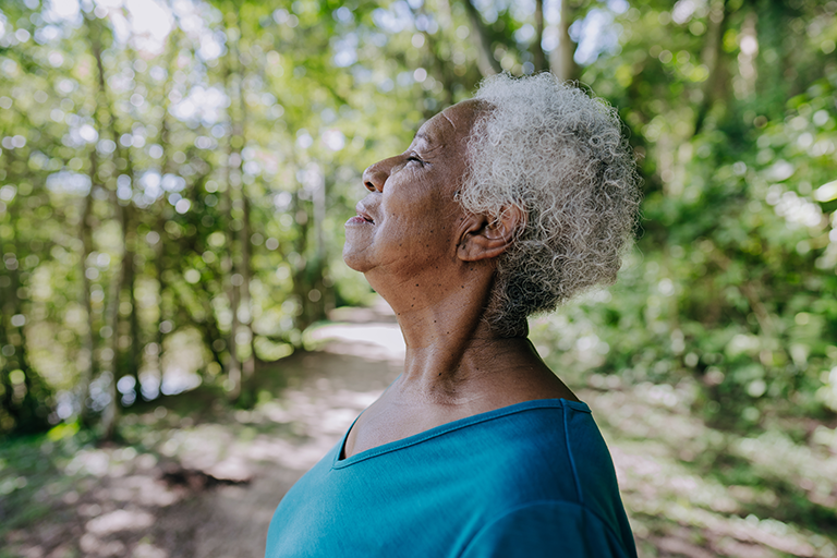 An older woman outside taking deep breaths