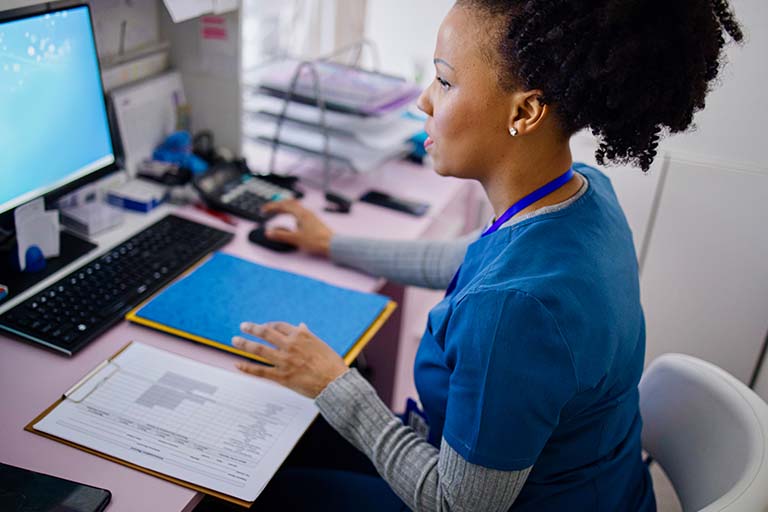 Nurse at computer updating records.