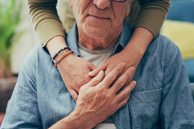 Recognizing the signs of dementia Image of an older man sitting with a caregiver hugging him