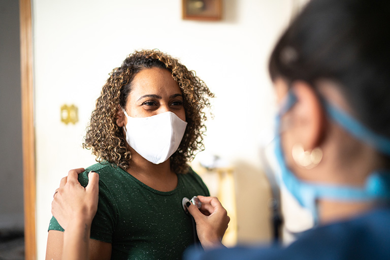 Cold and flu season is here, and instED can help Clinician wearing a mask talking to a member also wearing a mask