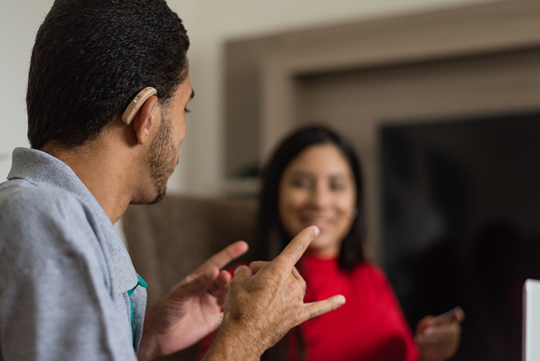 A person speaking sign language to a person who is deaf.