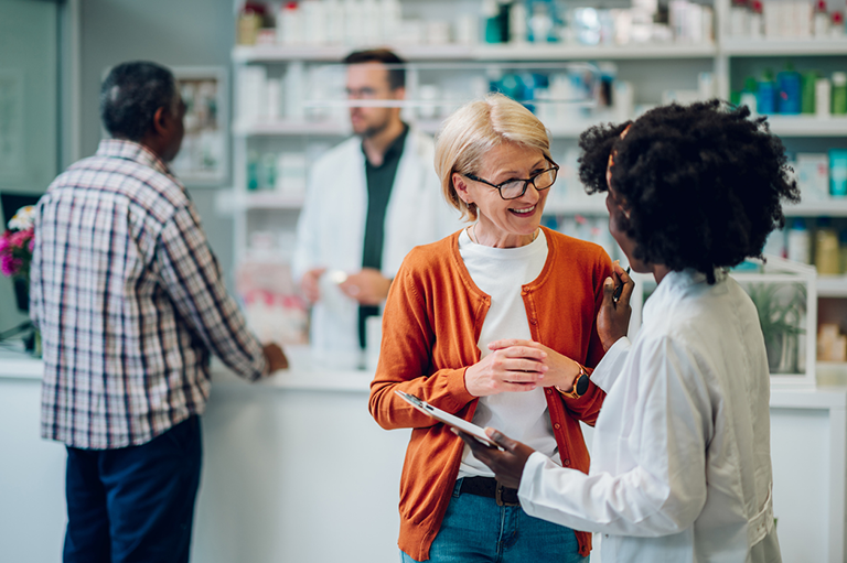 CCA’s new Pharmacy Benefit Manager is live: Take action now to avoid medication gaps for your patients People standing and chatting in a pharmacy.