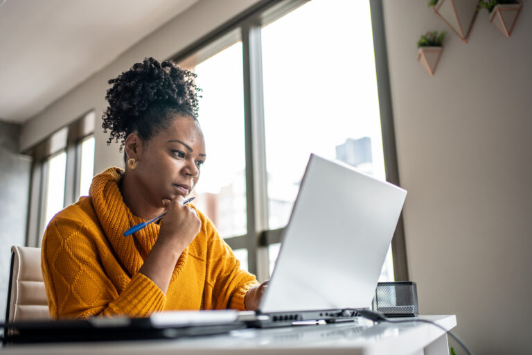 woman in yellow sweater at laptop
