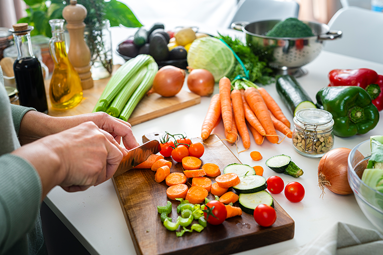 A woman's hands seen chopping vegetables on a cutting board.