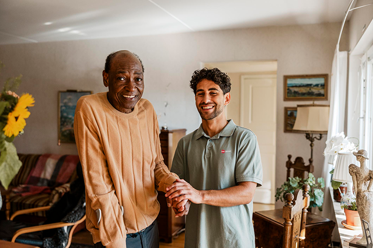A CCA member standing in his living room next to a CCA care team member