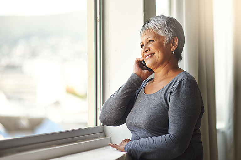 Older woman on the phone, standing by a window